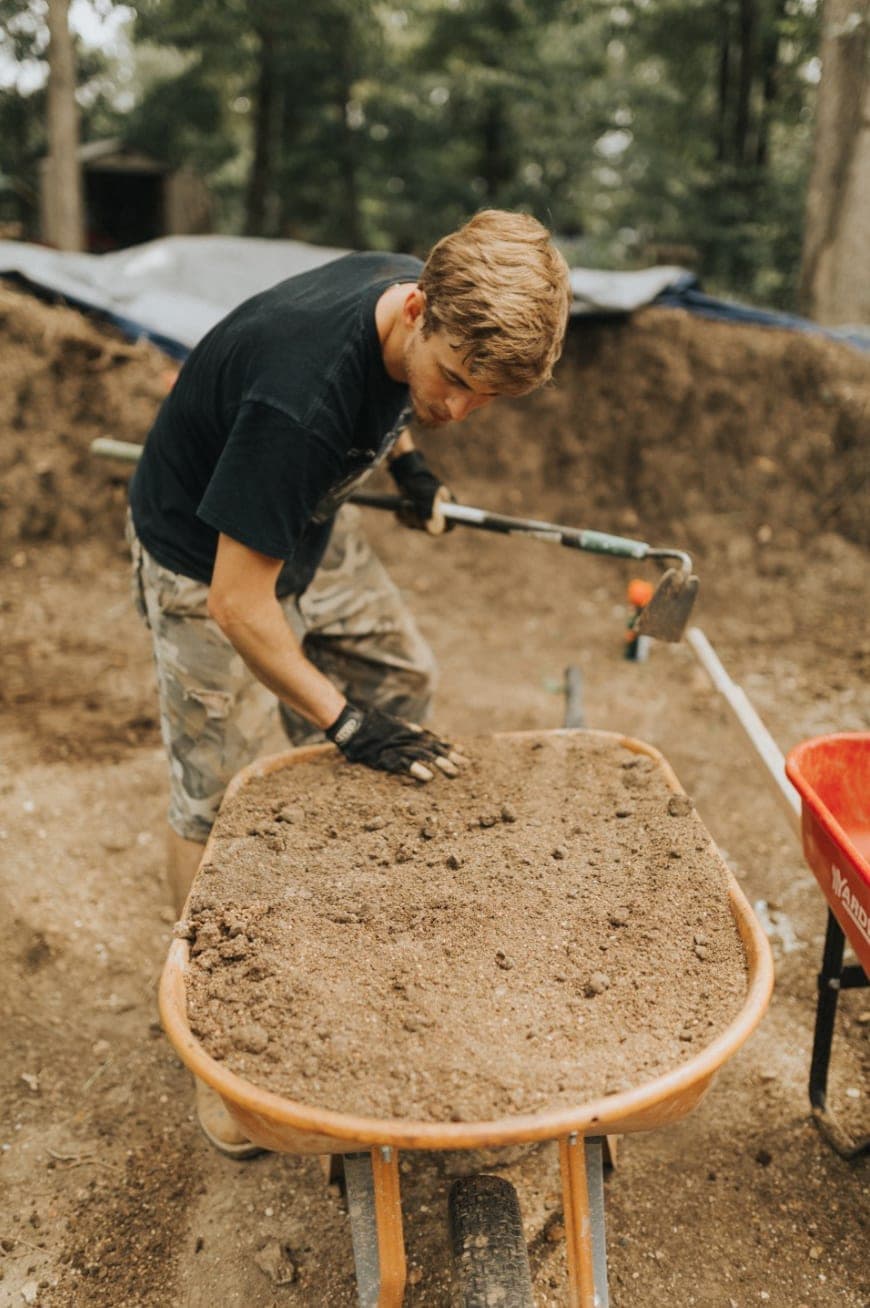 Neal mixing earthen building material in a wheelbarrow at the construction site